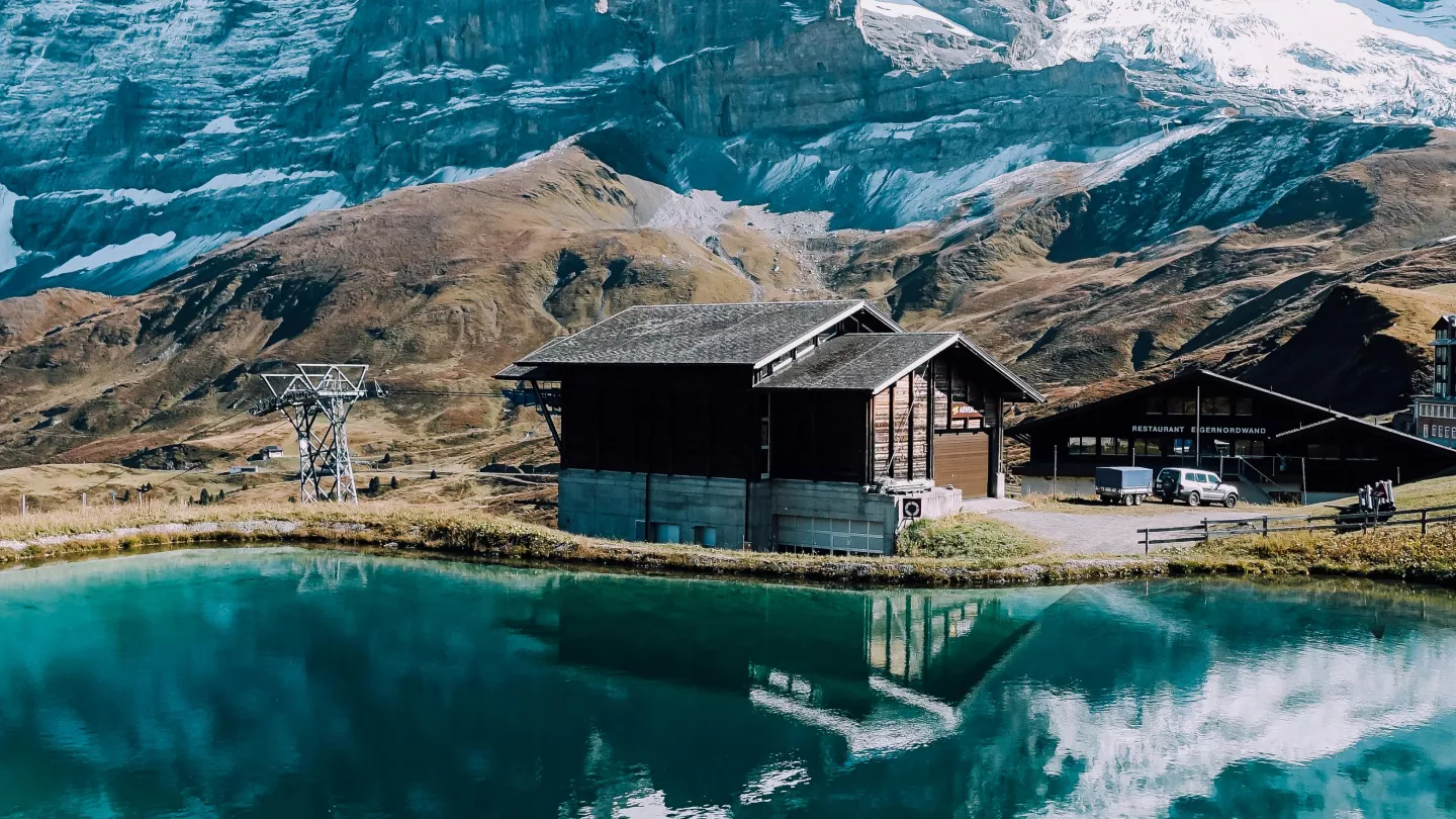 A mountain lodge is mirrored in the calm waters of a lake