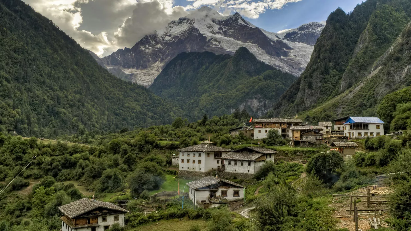 Two people sit on rocks beside a cascading waterfall