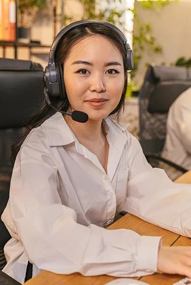 A woman wearing a headset sits at a desk, focused on her work